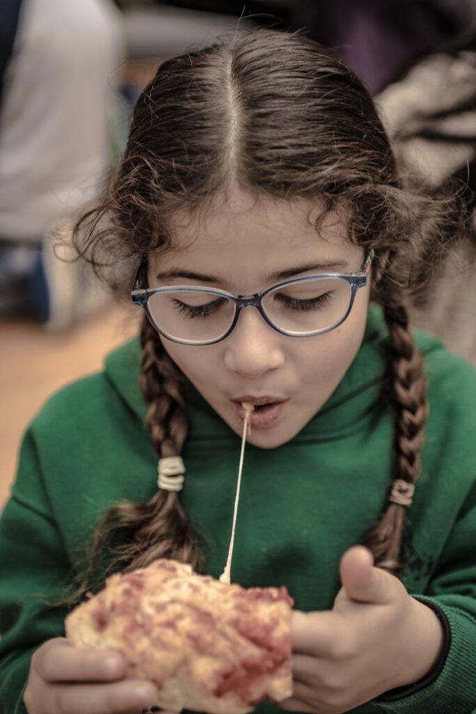 a young girl eating a piece of pizza
